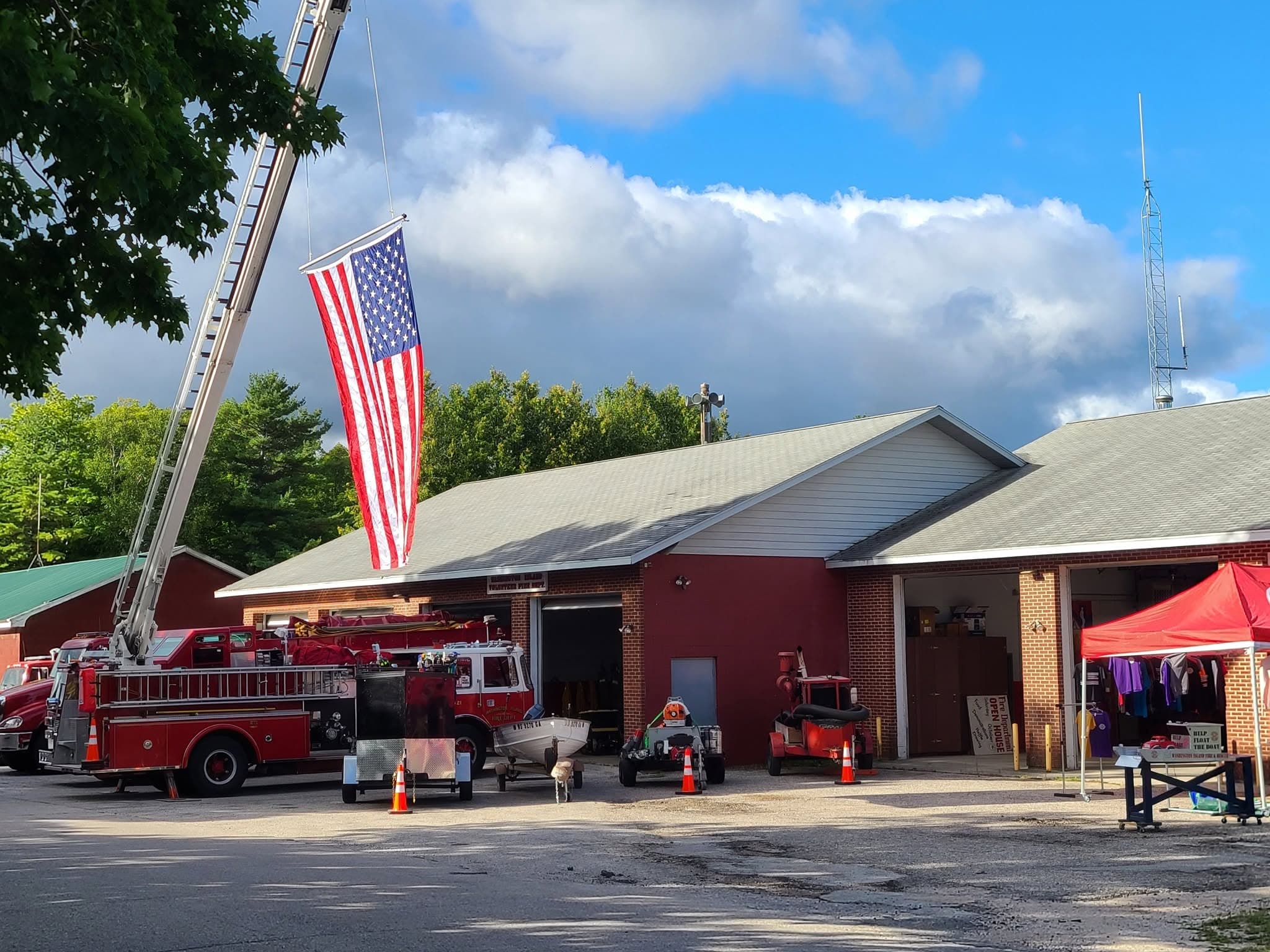 Washington Island fire station with a ladder truck, rescue equipment, fundraising tent, and large American flag