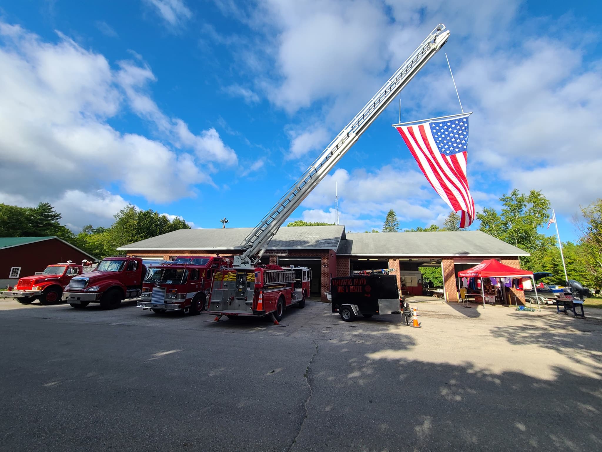 Washington Island Fire & Rescue engines lined up at the station with the ladder extended and American flag flying